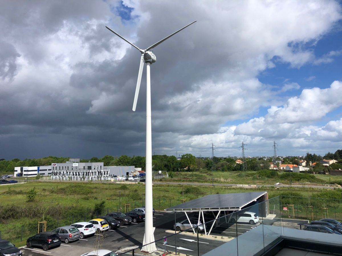 Installation éolienne de 25 kW sur un mât autoportant basculant et carport solaire photovoltaïque Installation éolienne de 25 kW sur un mât autoportant basculant et carport solaire photovoltaïque